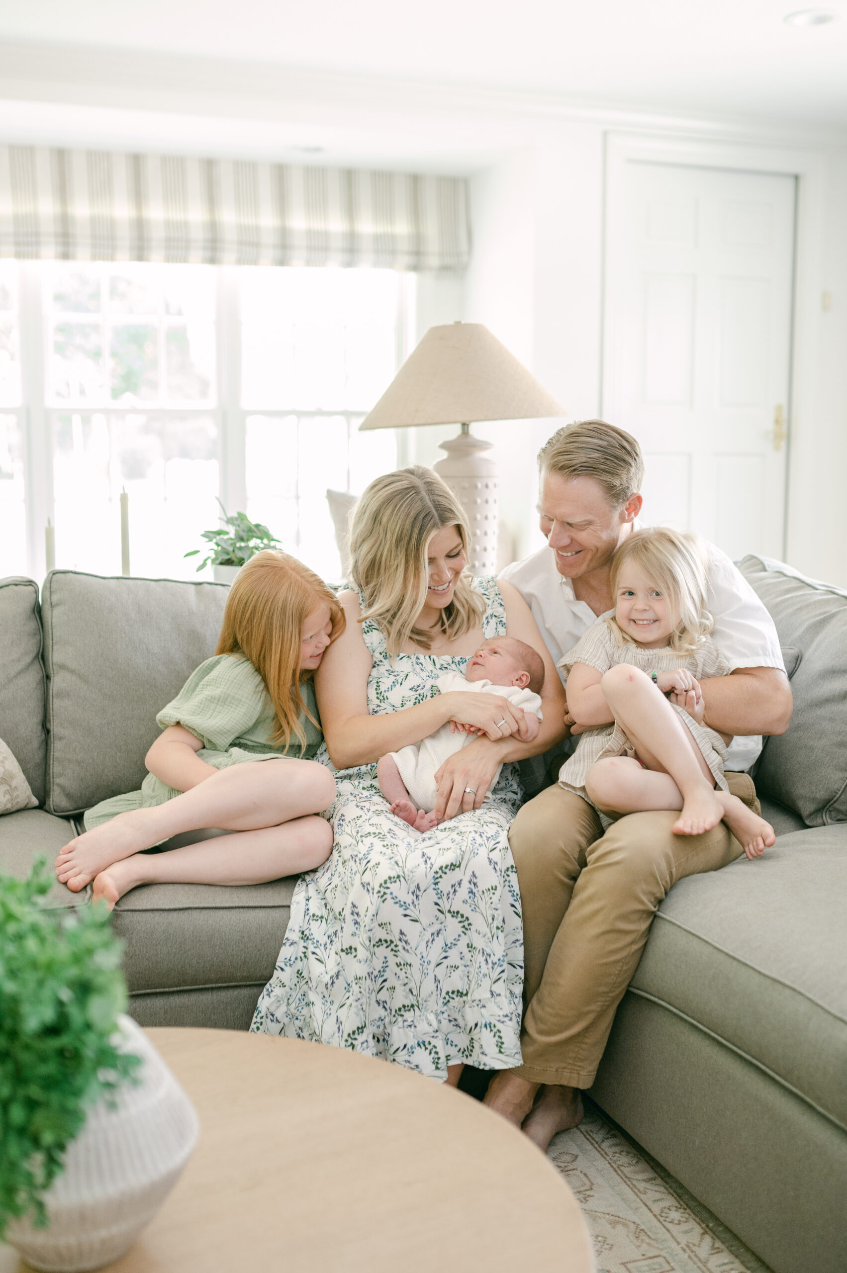 Family of five snuggles in their living room on the couch during a newborn session with Abby Park Photography 
