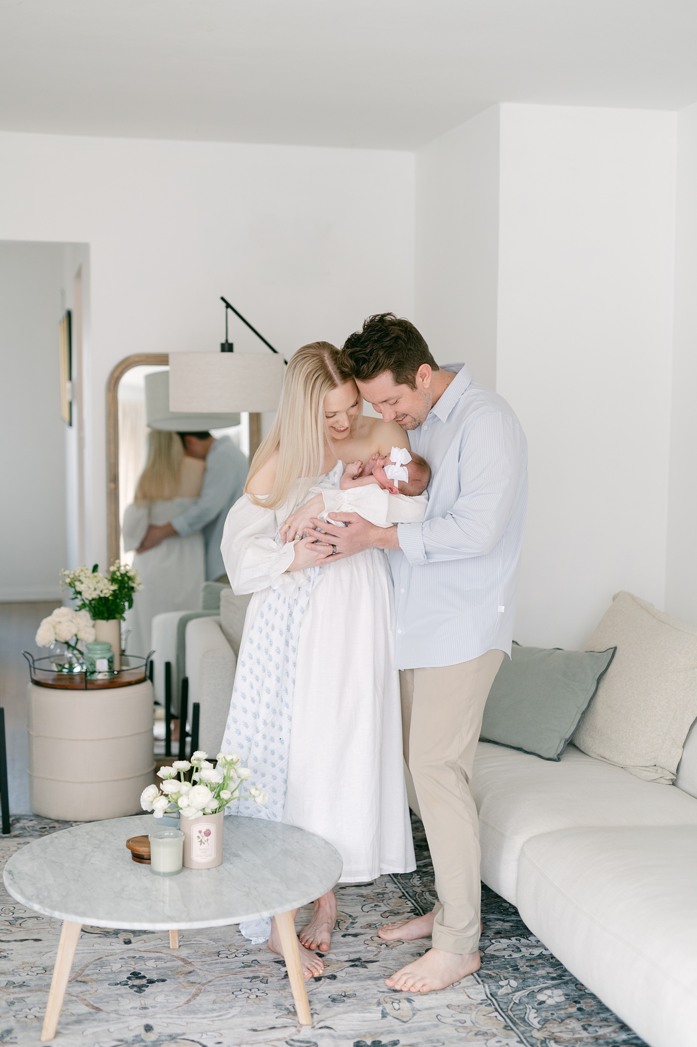 Mom and dad hold their baby in the living room during a newborn photography session with Abby Park Photography