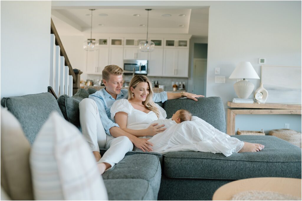 Mom and dad sit on couch with baby during a photography session with Abby Park Photography