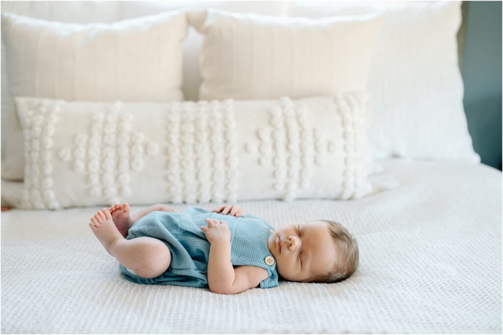 Sleeping baby lays on bed during photo session with Abby Park Photography