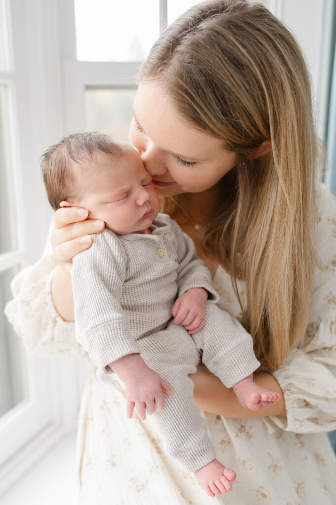 Milwaukee newborn photography session with mom kissing baby