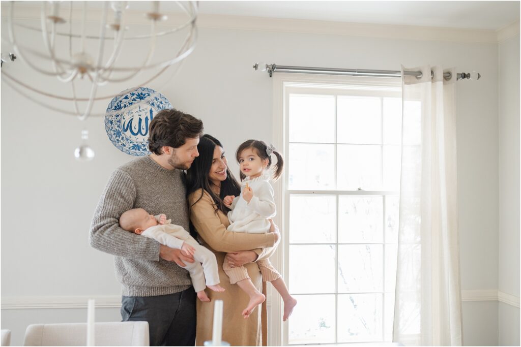 Family holding their two little girls in their dining room in Whitefish Bay, Wisconsin during an in-home newborn session