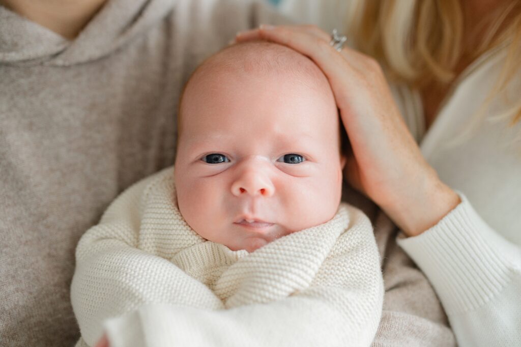 close up image of two month old baby with mom's hand on head