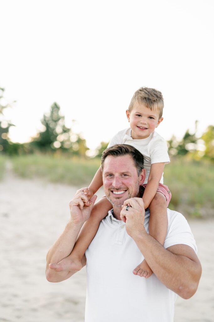 Son riding on his dad's shoulders at the beach 